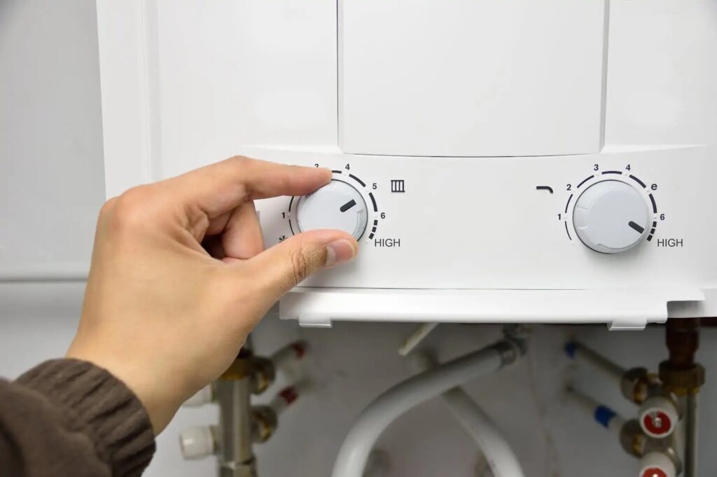 Hand adjusting dial on tankless water heater to change temperature setting