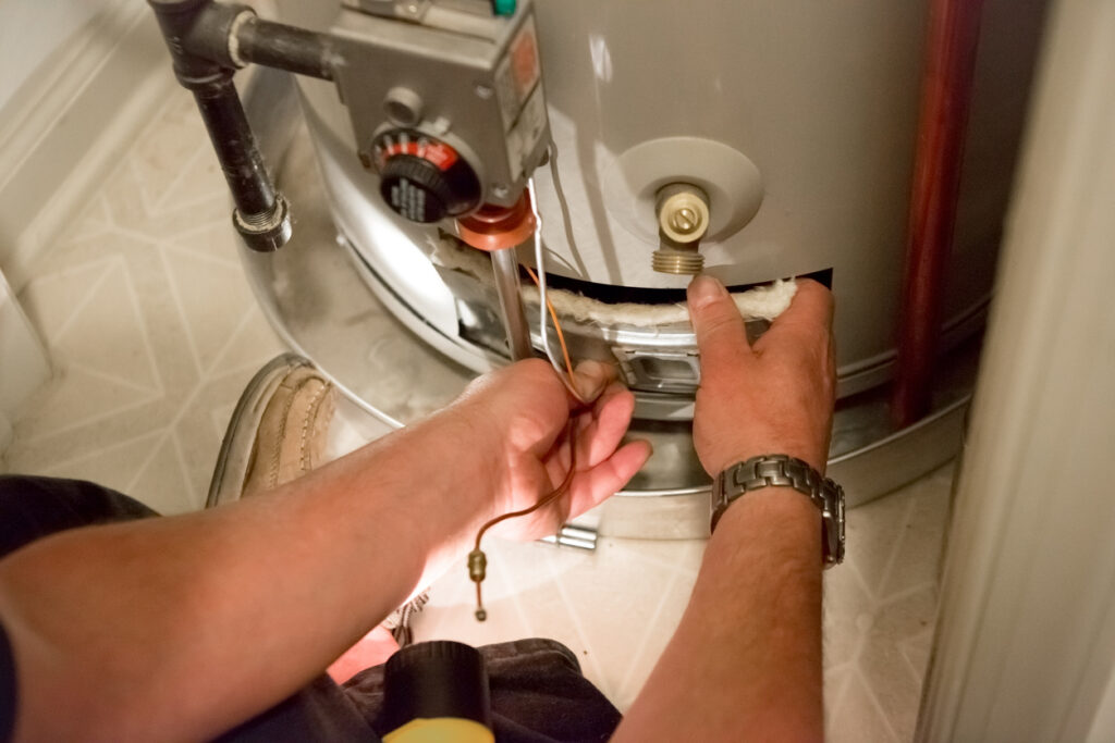 Man using tool to work on water heater in small storage closet